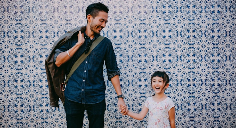 Japanese father and his preschool mixed race daughter on street of Portugal with azulejo tile wall